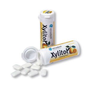 Weiße Kaugummistücke in einer geöffneten runden Dose mit gelbem Etikett und fruchtigem Design