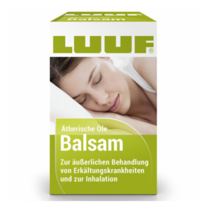 Verpackung des LUUF Balsams mit Aufschrift zu ätherischen Ölen und Anwendung bei Erkältungen, abgebildet auf einem Kissen.