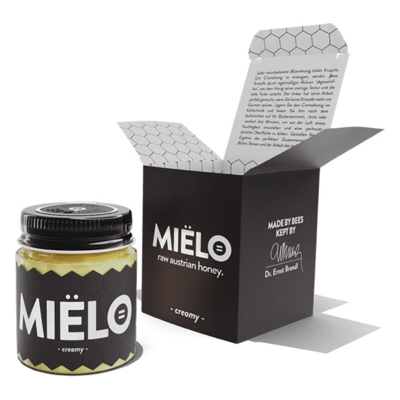 Ein Glas mit cremigem, rohem österreichischen Honig in schwarzer Verpackung mit einem offenen Deckel und beschreibendem Inhalt.